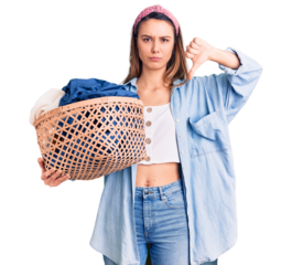 Young beautiful girl holding laundry basket with angry face, negative sign showing dislike with thumbs down, rejection concept