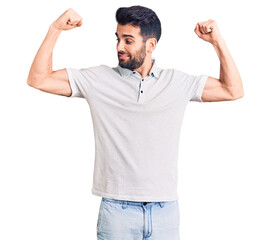 Young handsome man with beard wearing casual polo showing arms muscles smiling proud. fitness concept.