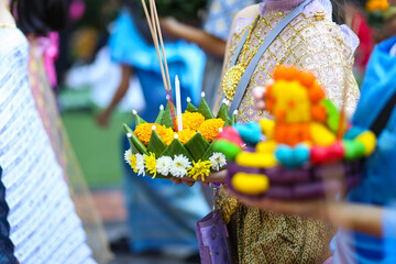 
Thai people hold a krathong that is a beautiful small basket made from a piece of a banana tree trunk and decorated with banana leaves, flowers, incense sticks and a candle.  - obrazy, fototapety, plakaty