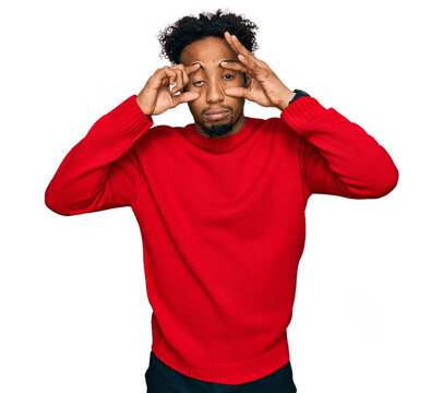 Young african american man with beard wearing casual winter sweater trying to open eyes with fingers, sleepy and tired for morning fatigue