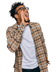 Young african american man with beard wearing casual clothes and glasses shouting and screaming loud to side with hand on mouth. communication concept.