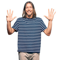 Handsome caucasian man with long hair wearing casual striped t-shirt showing and pointing up with...