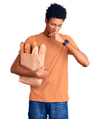 Young african american man holding paper bag with bread feeling unwell and coughing as symptom for cold or bronchitis. health care concept.