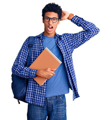 Young african american man wearing student backpack holding book crazy and scared with hands on head, afraid and surprised of shock with open mouth