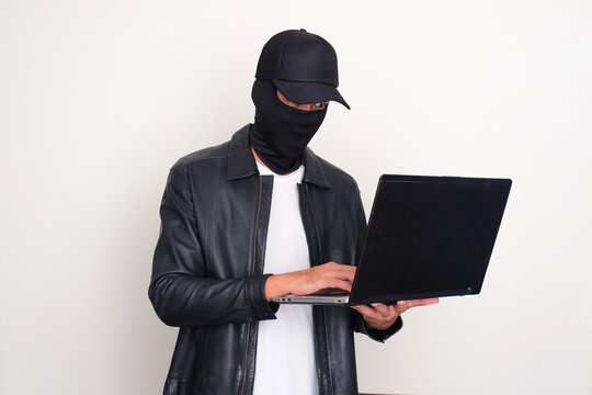 An online hacker looking doing data breaching on a laptop