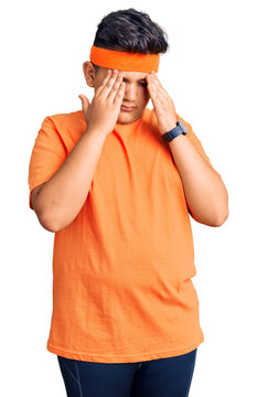 Little boy kid wearing sportswear with hand on head, headache because stress. suffering migraine.