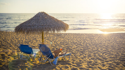 Young woman on beach relaxed with cocktail on sunbed  at sunset