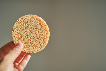 A large natural sponge in a womans hand.