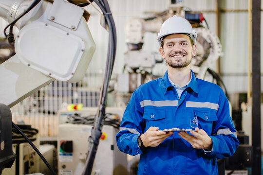 portrait happy smiling engineer service staff worker in robotic workshop robot arm plant assembly industry.