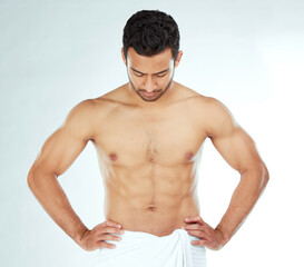 Fototapeta premium Body, cleaning and asian man in a towel in studio for wellness, hygiene or grooming on white background. Stomach, chest and male model checking fitness results, progress or sixpack muscle development