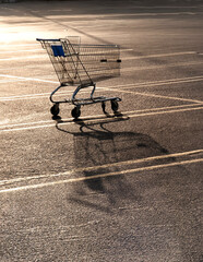  A Lone shopping cart in an empty parking lot  in afternoon light