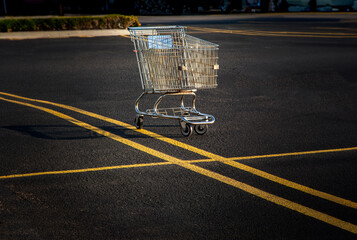  A Lone shopping cart in an empty parking lot  in afternoon light
