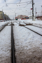 Snow-covered tramway tracks. Streetcars are waiting at the depot. The tracks are covered in snow.