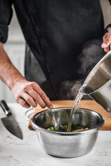 Fototapeta na wymiar Chef blanching broccoli in a hot water with lemon