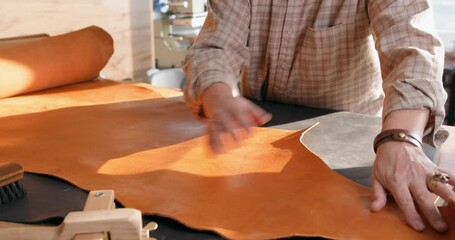 thoughtful talented old artisan holding the roll of leather preparing to make some leather goods for sale, business, lifestyle, hobby, free time