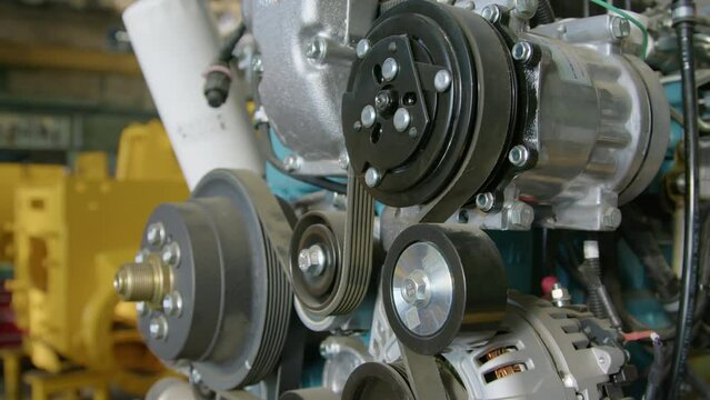 No people side closeup of multiple sheeves or pulleys of tractor explosion engine connected with flexible element at manufacturing factory