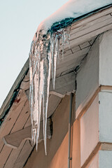 Fototapeta premium An icicle on the eaves of the roof on a winter day