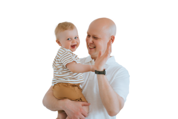 Bald caucasian man playing with toddler son against transparent background. Fatherhood, childhood. Healthy kids, family relations. Cute little boy smiles looks at camera hugs father.