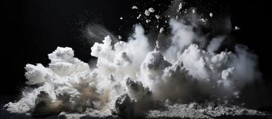 Stone debris explodes, scattering white powder against black backdrop. - obrazy, fototapety, plakaty