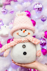 A girl holds a snowman on the background of a Christmas tree
