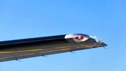 Position light on the wing of the plane, Red navigation light on left wing of jet airplane.