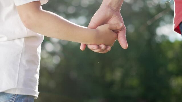 happy family father and daughter hold hands close up. Dad and baby girl hands together at sunset. Father Day. Dad and daughter are holding hands. A father extended a helping hand to his daughter child