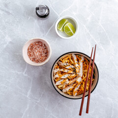Traditional Asian noodles with vegetables and chicken in a bowl