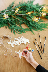 Painting festive wooden reindeer ornaments on craft table