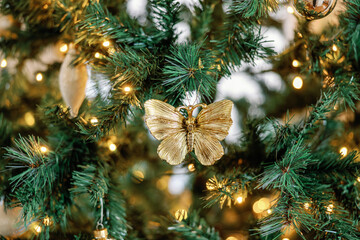 Obraz na płótnie Canvas Gold butterfly ornament on lit Christmas tree