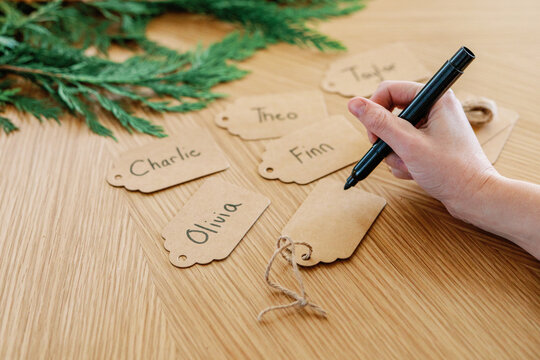 Handwriting names on holiday gift tags, one still blank