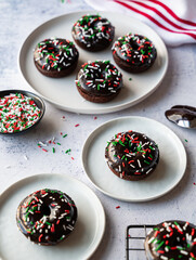 Close up of plates of chocolate donuts with Christmas sprinkles.