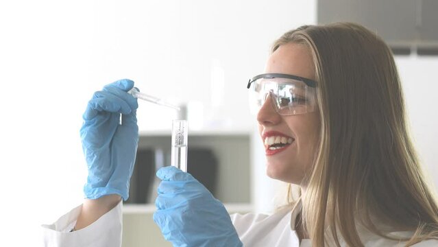 Young scientist female with lab glasses pipetting