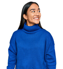 Young asian woman wearing casual winter sweater looking away to side with smile on face, natural...