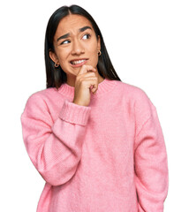 Young asian woman wearing casual winter sweater thinking worried about a question, concerned and...