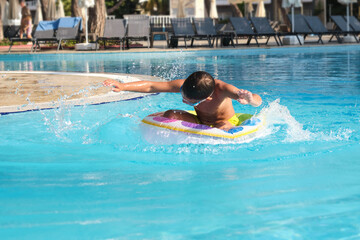Childhood's simple pleasures: boy immersing himself in pool fun with a playful splash