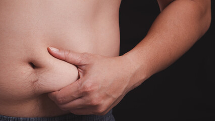Closeup of man fat belly with hand holding on it. Obesity body, overweight and health problem from unhealthy eating lifestyle concept.