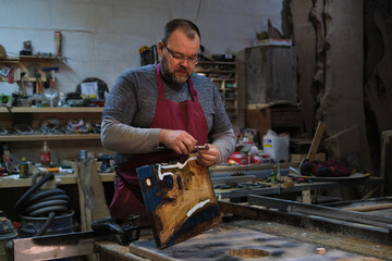 Woodworker shaves wood; immersed in the task. Reflects the need for quality in fast-paced times.