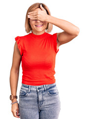 Young blonde woman wearing casual clothes smiling and laughing with hand on face covering eyes for surprise. blind concept.