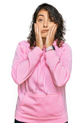 Young hispanic woman wearing casual sweatshirt tired hands covering face, depression and sadness, upset and irritated for problem