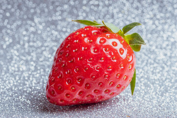 Red ripe strawberries with green leaves on a shiny silver white background. Fruit background. Ripe...