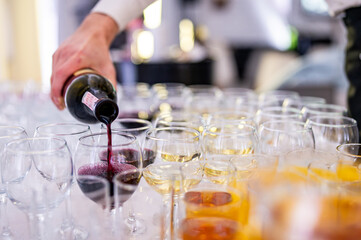waiter pouring red wine from bottle into a glass in cafe or restaurant