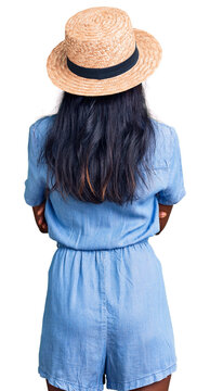 Young indian girl wearing summer hat standing backwards looking away with crossed arms