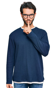 Young hispanic man wearing casual clothes and glasses asking to be quiet with finger on lips. silence and secret concept.