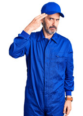 Middle age handsome man wearing mechanic uniform shooting and killing oneself pointing hand and fingers to head like gun, suicide gesture.