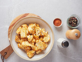 Top view of raw cauliflower florets on a plate seasoned with paprika, salt and pepper. Vegetable ingredient. Food preparation.