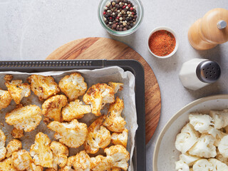 Cauliflower florets seasoned with paprika, salt and pepper on a oven tray ready to roast.