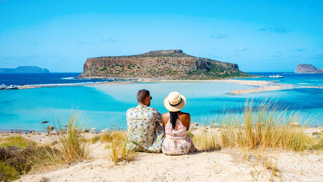 Crete Greece Balos Lagoon Tourists relax at the crystal clear ocean of Balos Beach, a couple of men, and a woman visit the beach during a vacation in Greece