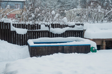 winter snow covered outside hot tub made of wood on front porch
