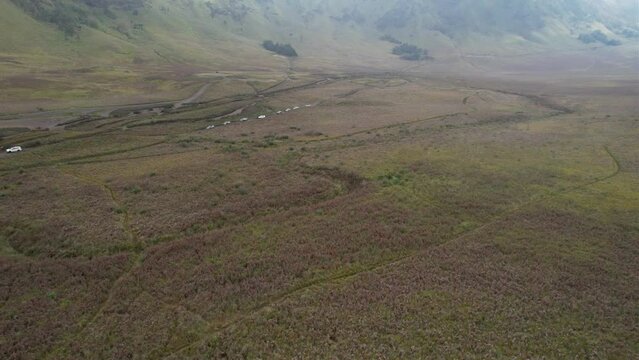 Aerial view of car across huge savanna with foggy mountains in the background
