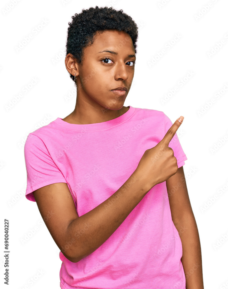 Wall mural Young african american woman wearing casual clothes pointing with hand finger to the side showing advertisement, serious and calm face